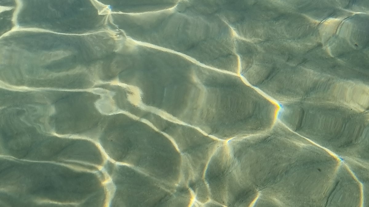 Light reflections on clear, shallow seawater in the Mani