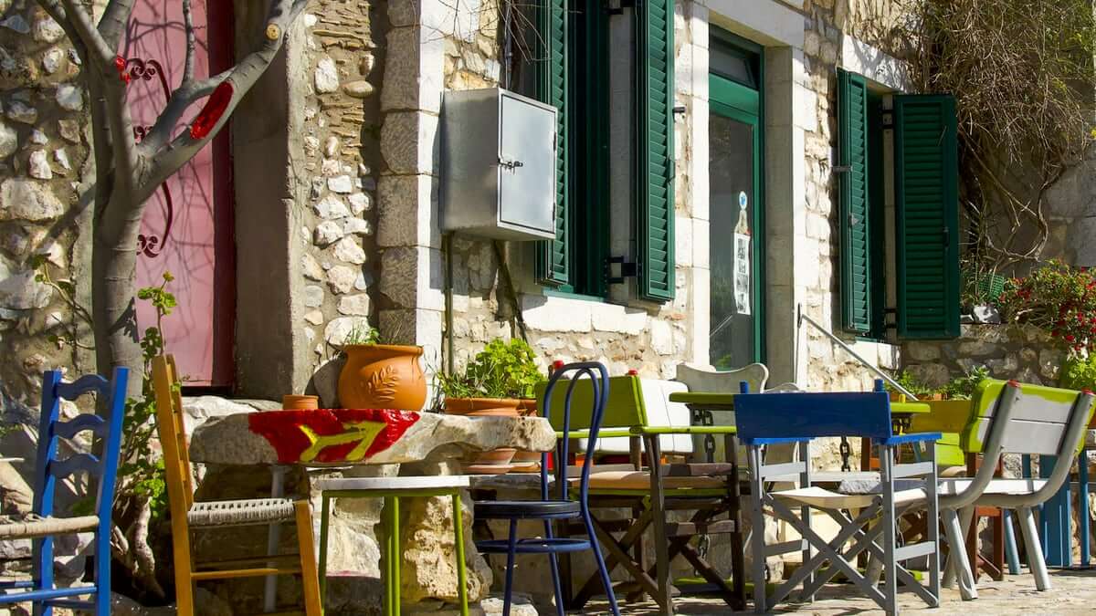 Traditional taverna in the Mani with colourful chairs and green shutters