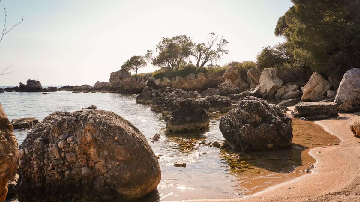 Rocky swimming cove in the Mani with clear water and a small sandy beach