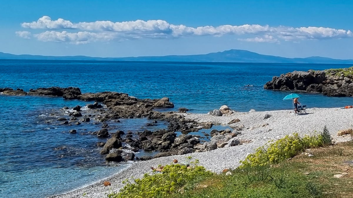 White pebble beach in the Mani with blue sea and rocks